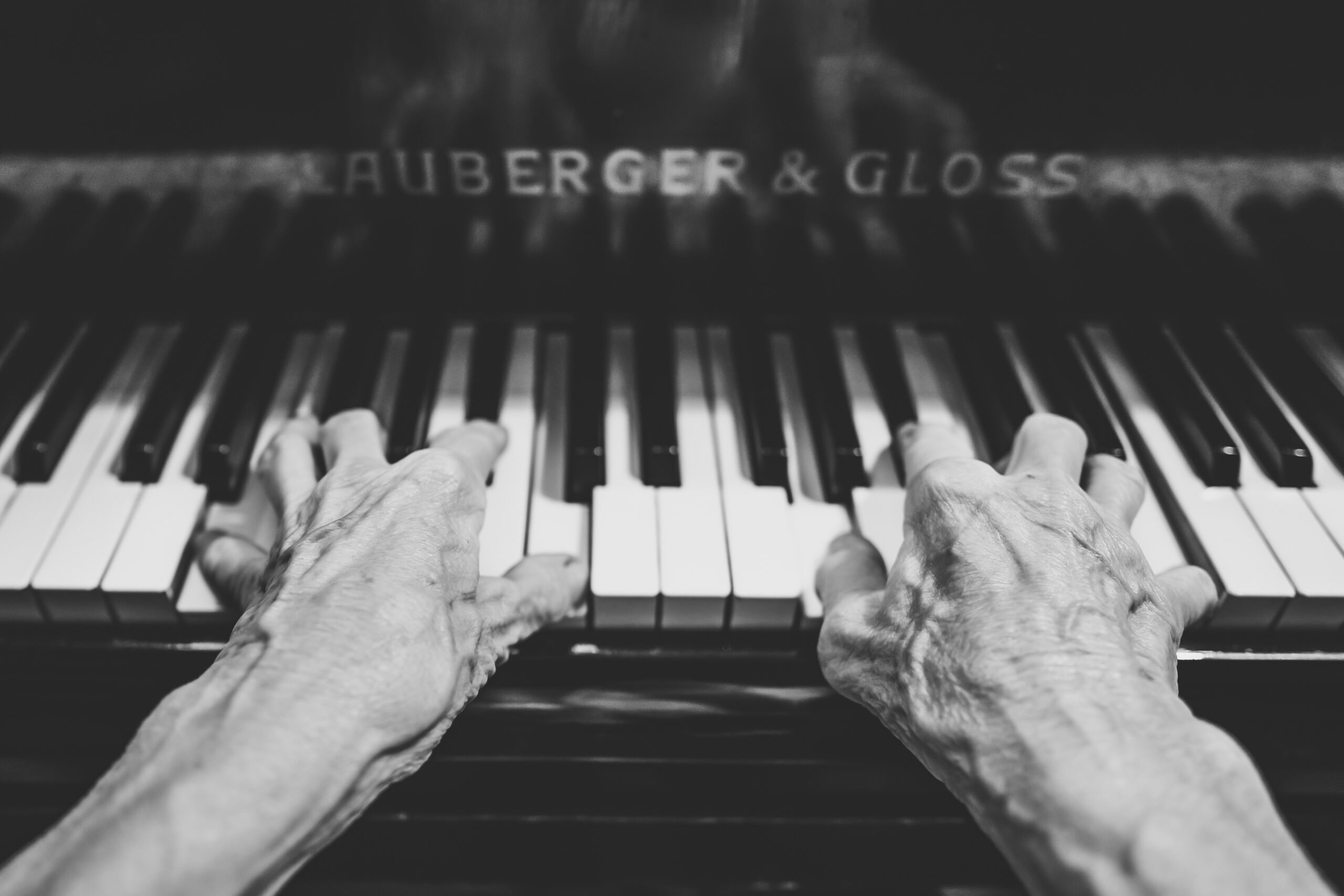 Iäkkäät kädet soittavat pianoa mustavalkoisessa Cuporen Taide, kulttuuri ja hyvinvointi -arviointiraportin uutisointikuvassa.. Kuvaaja Lukas Budimaier, Unsplash.